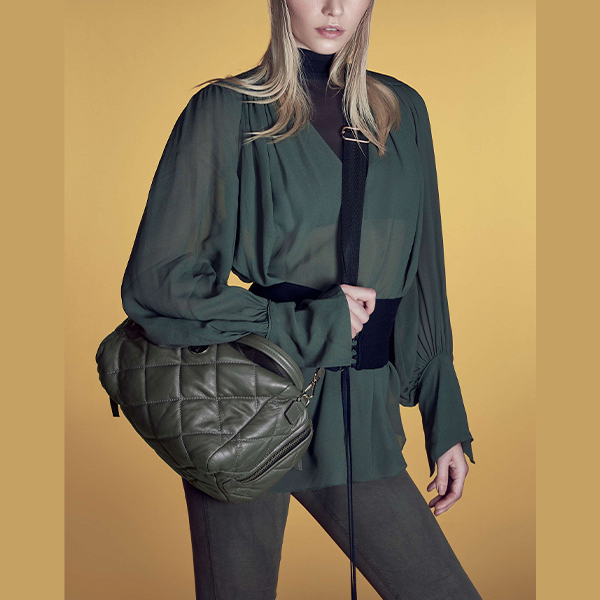 mulher usando casaco e calça verde militar com bolsa de couro verde