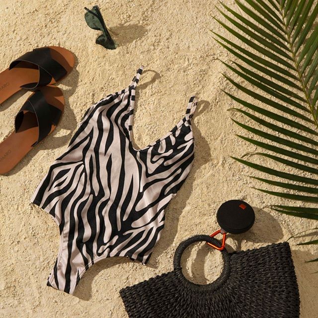 imagem flatlay na praia com maiô, chinelo, bolsa de praia e óculos de sol